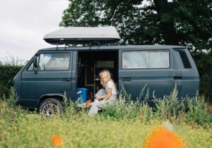 A woman sitting in her campervan with the side door open