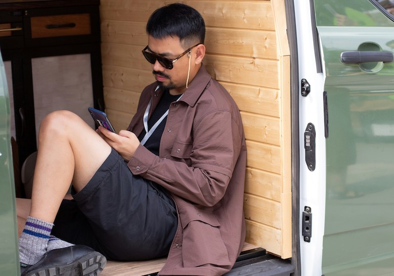 A man using his phone while sat in a van conversion