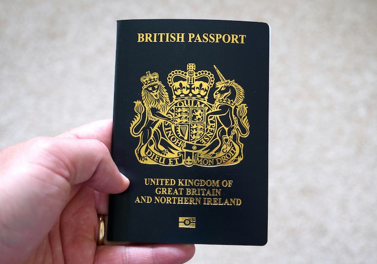 A hand holding a new, blue UK passport