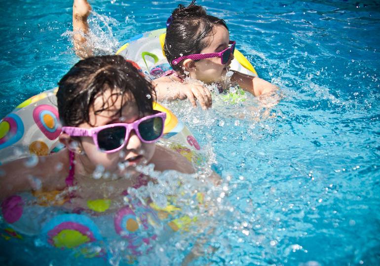 Two girls in rubber rings in a swimming pool