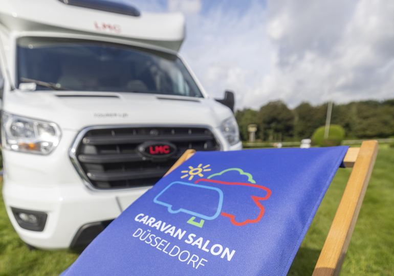 A deck chair featuring the Caravan Salon logo in front of a motorhome