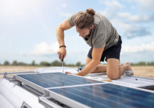 Person working on solar panels on top of a van