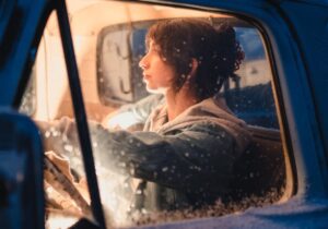 A woman in the cab of a motorhome, with snow on the window