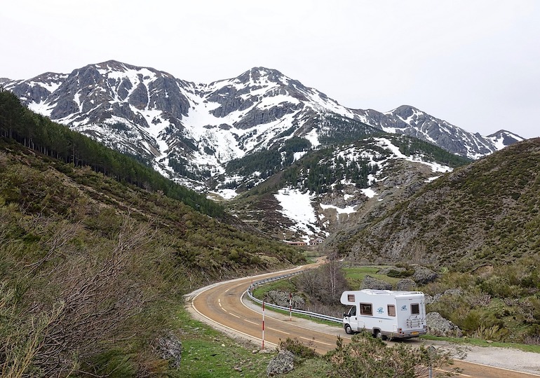 A motorhome driving towards snowy mountains