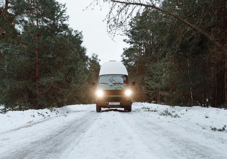 A campervan driving along a snowy road