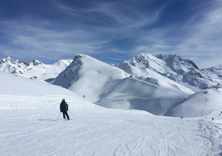 A skier set against a background of snowy mountains